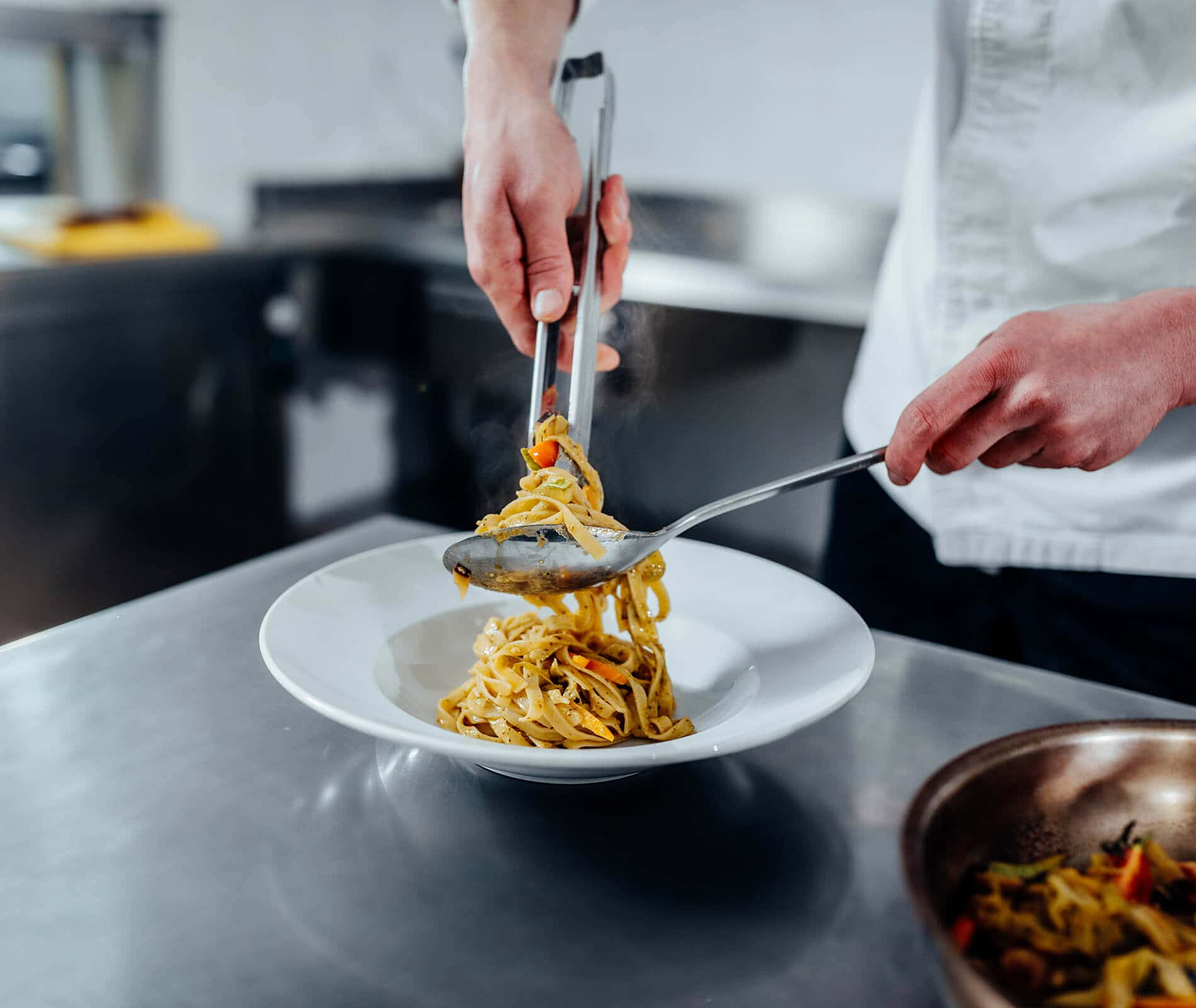 Piatto di pasta con un cuoco nel background